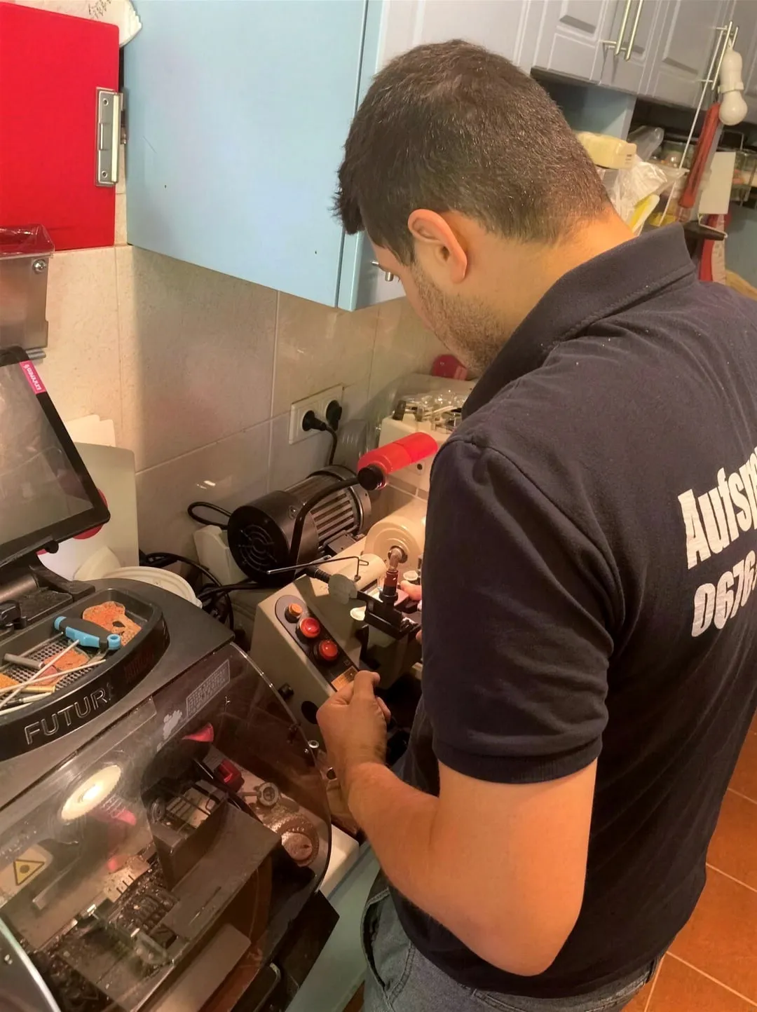 One of the sons cutting a duplicate key on the key machine in the workshop.